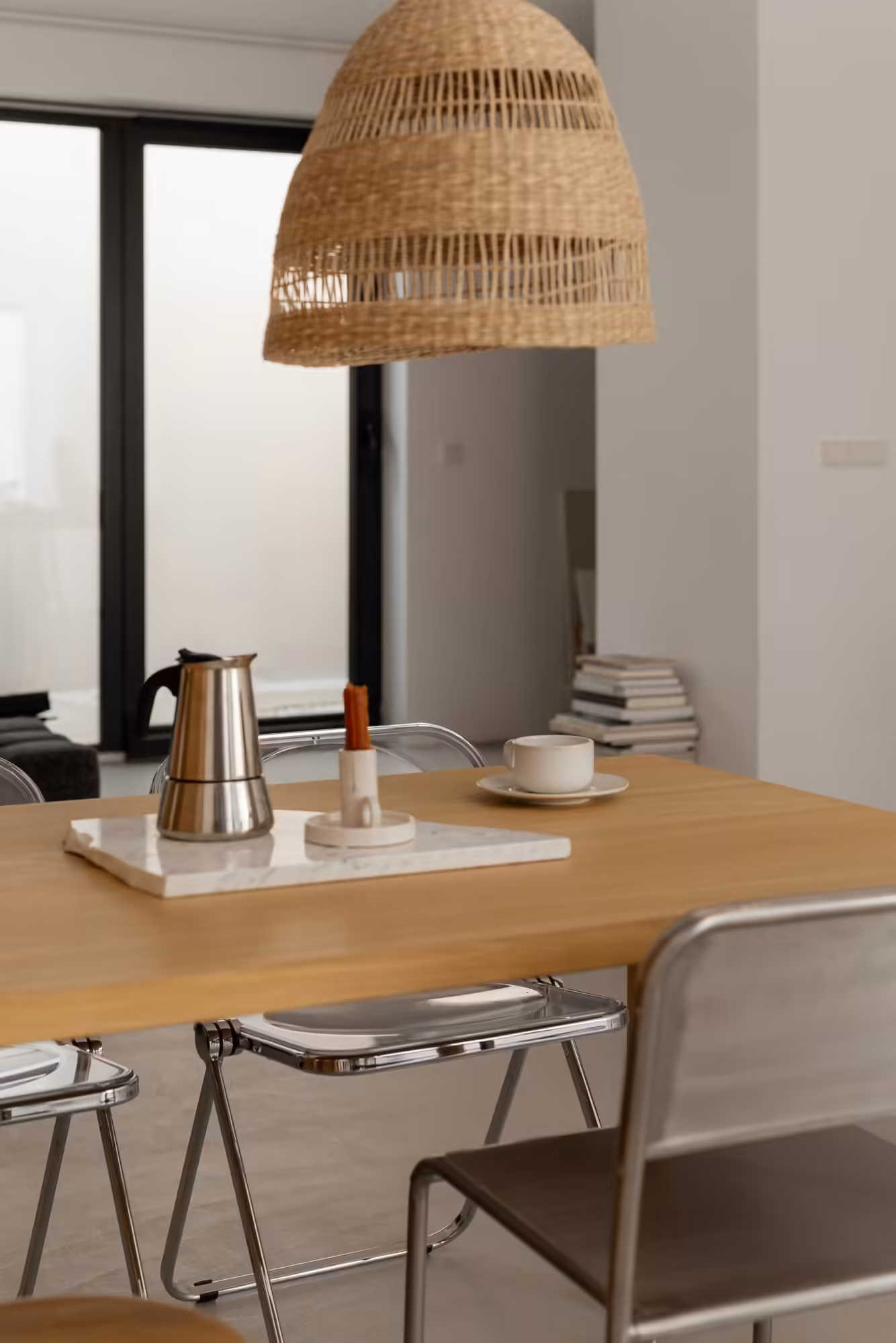 Holztisch mit Espressokocher und Tasse unter einer Rattan Pendelleuchte