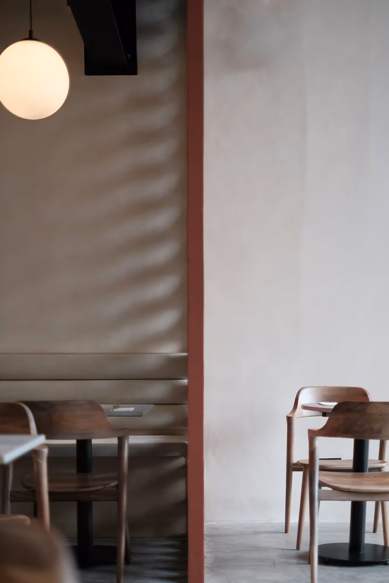 Café Interior mit Holzstühlen, Rundleuchte und rostroter Säule