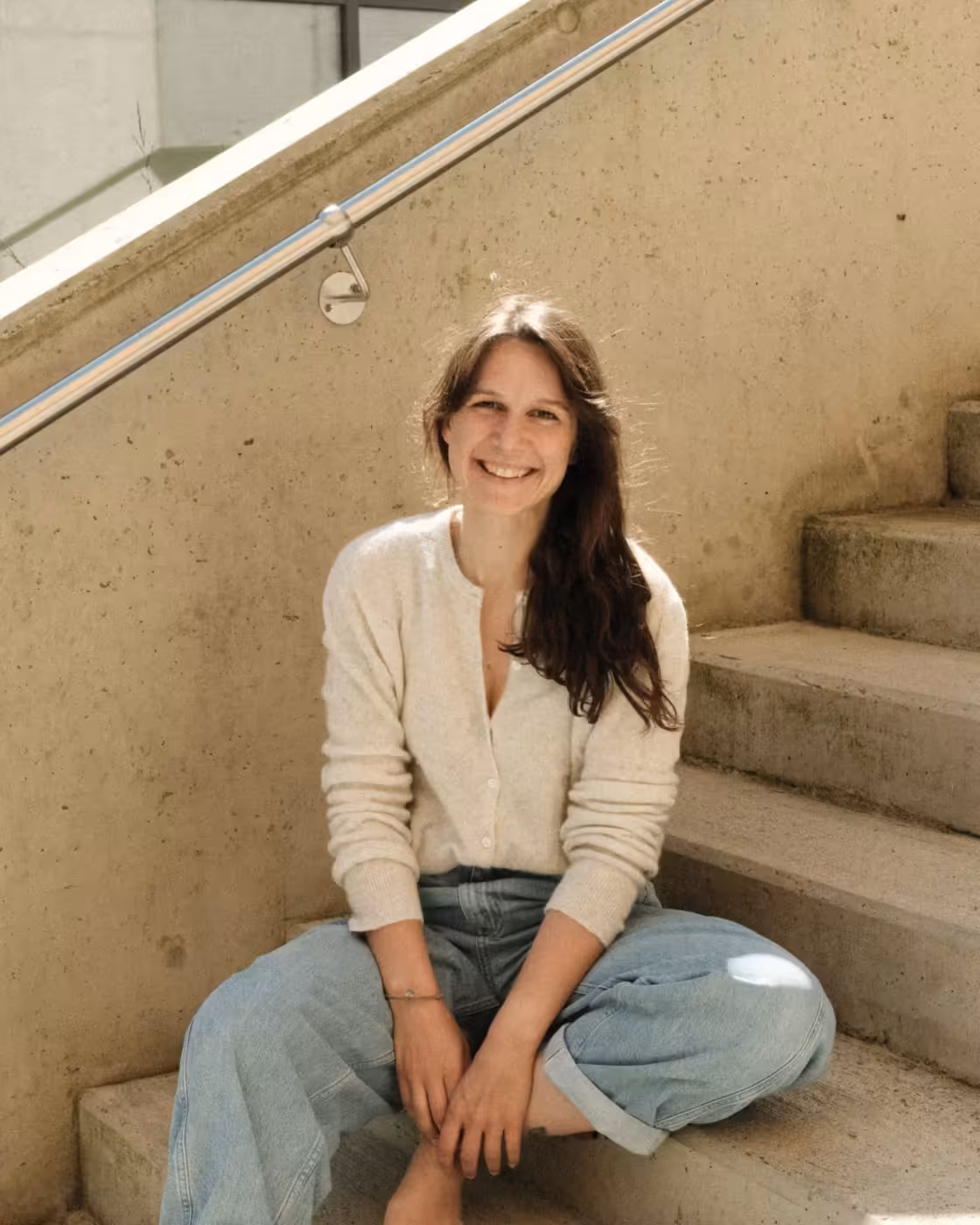 Anna von INFLOW lächelnd auf einer Treppe sitzend